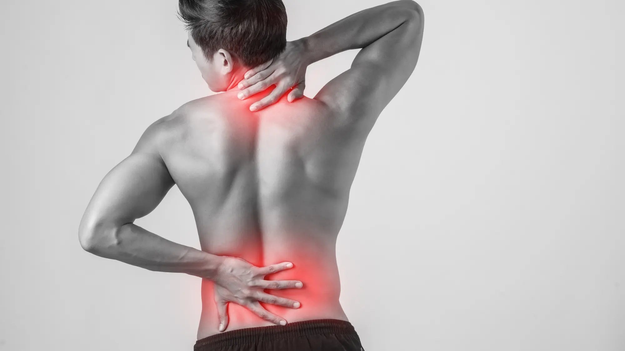 Mężczyzna stoi tyłem, trzyma się za kark i lędźwie. Te okolice zaznaczone są na czerwono, sygnalizując ból.