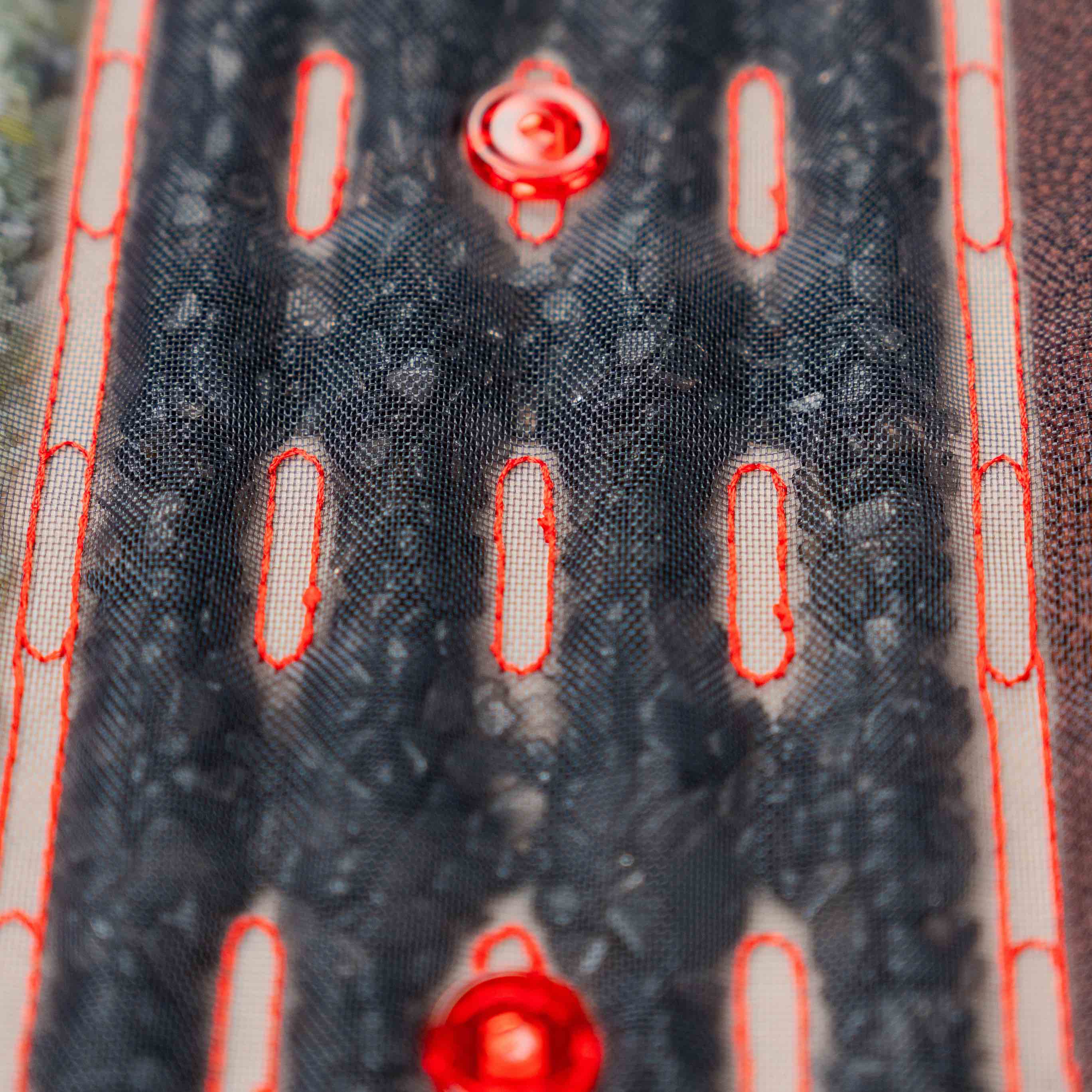 Zbliżenie na czarne kamienie masujące i czerwone diody LED w podgrzewanej macie masującej Casada, pokazujące strukturę i materiały zastosowane w urządzeniu.