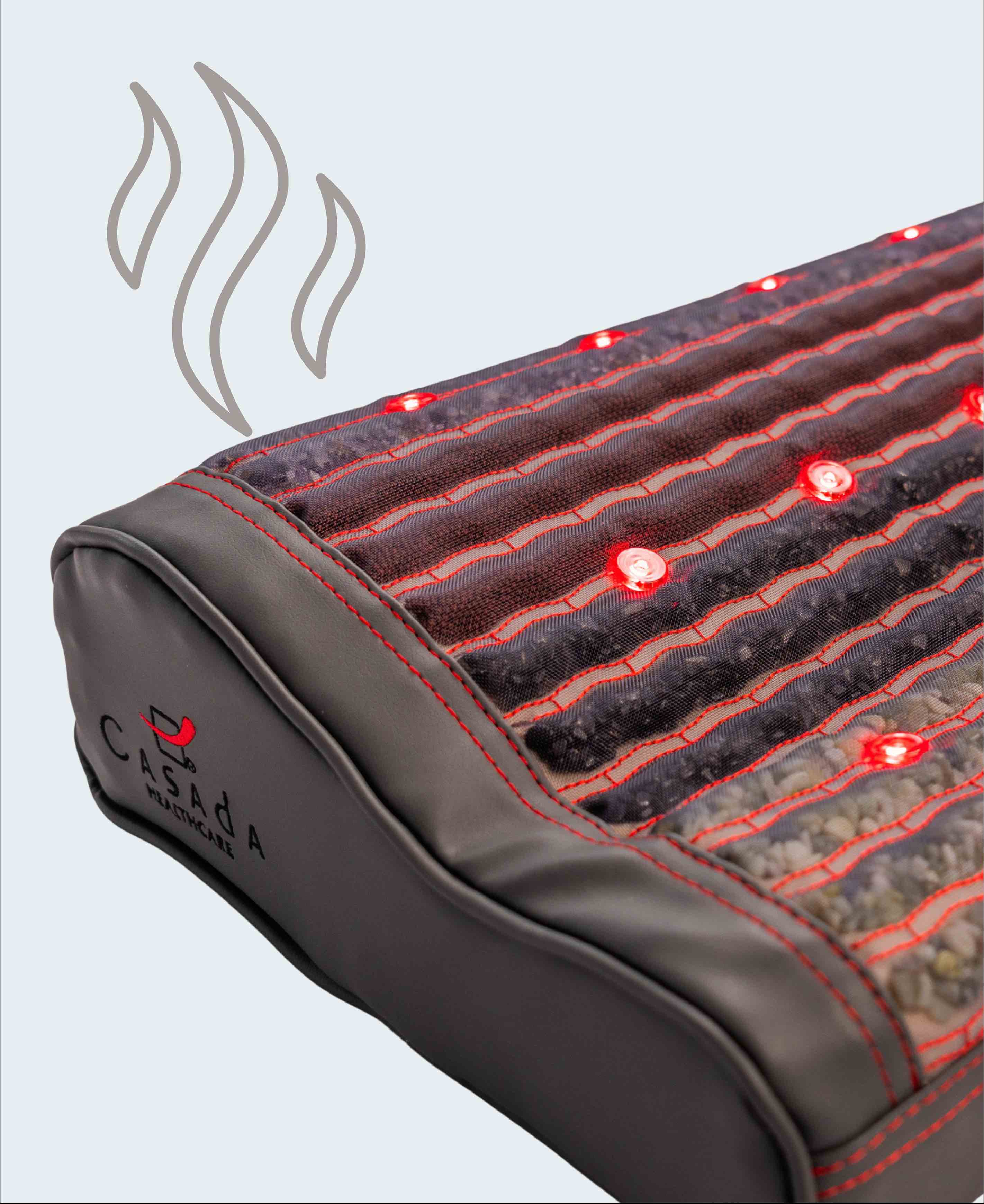 Zbliżenie na podgrzewaną matę masującą Casada z czerwonymi diodami LED i widocznymi kamieniami masującymi, symbolizującymi funkcję nagrzewania.