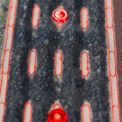 Zbliżenie na czarne kamienie masujące i czerwone diody LED w podgrzewanej macie masującej Casada, pokazujące strukturę i materiały zastosowane w urządzeniu.